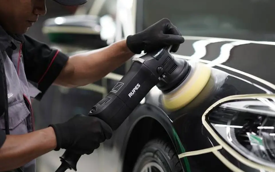 Profissional polindo o capô de um carro com politriz