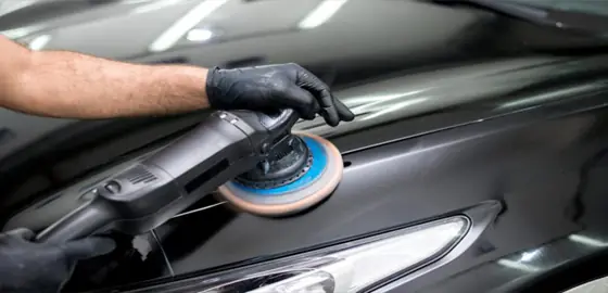 Politriz sendo usada no capô de um carro preto