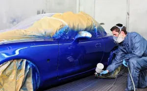 Profissional aplicando pintura automotiva em um veículo azul